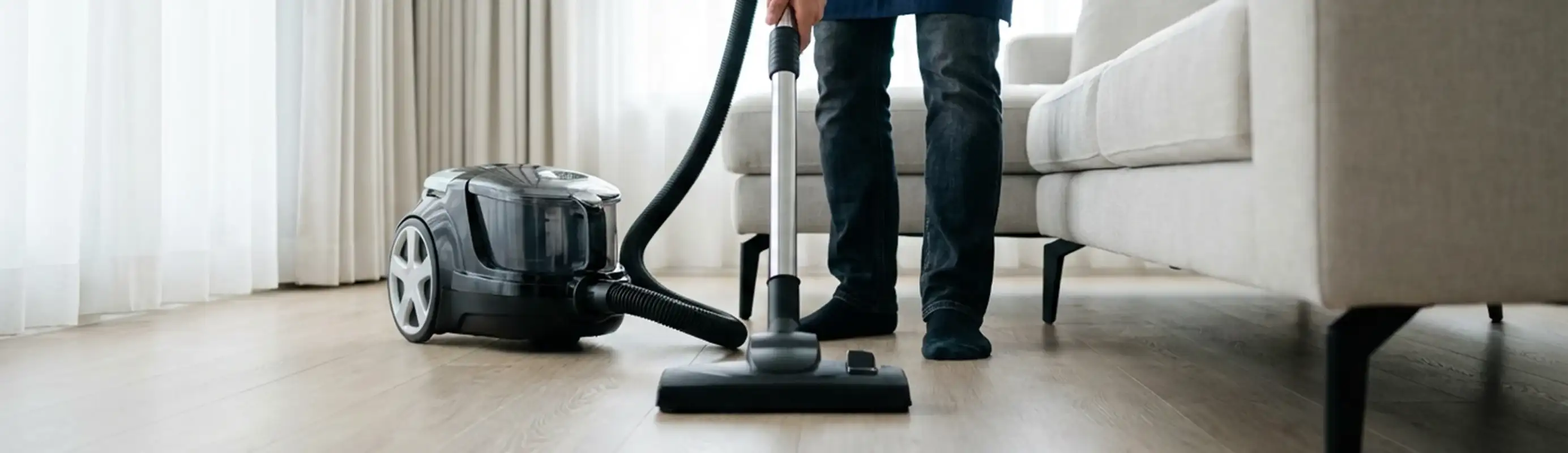 Professional house cleaner vacuuming a living room floor with a canister vacuum cleaner, South Bend, IN.